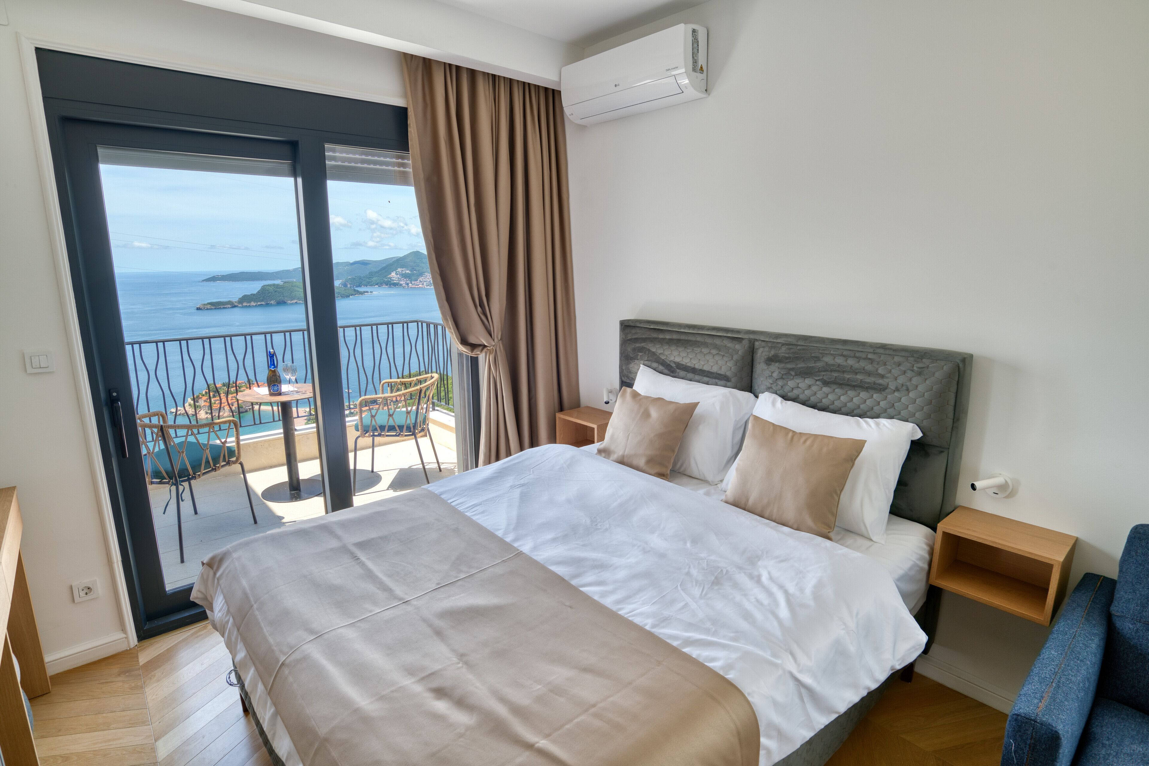 Une chambre avec un lit, une table de chevet, une chaise, un balcon avec vue sur la mer et un appareil de climatisation.
