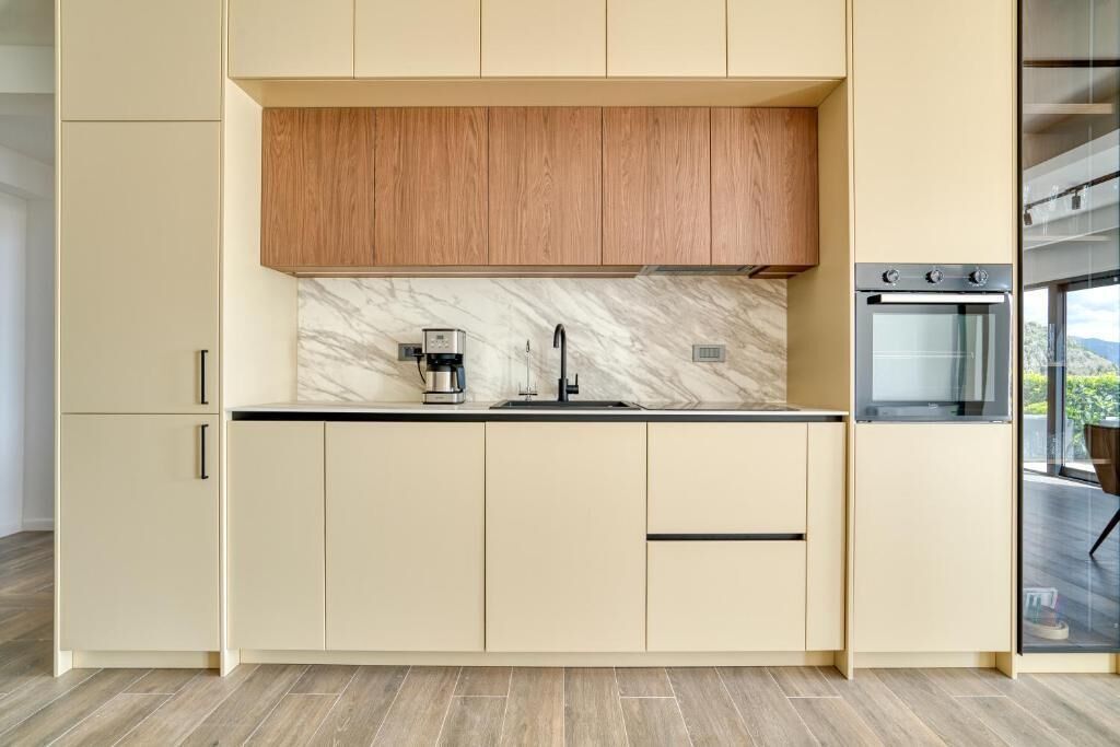 A modern kitchen with a marble backsplash, wooden cabinets, and a built-in oven.