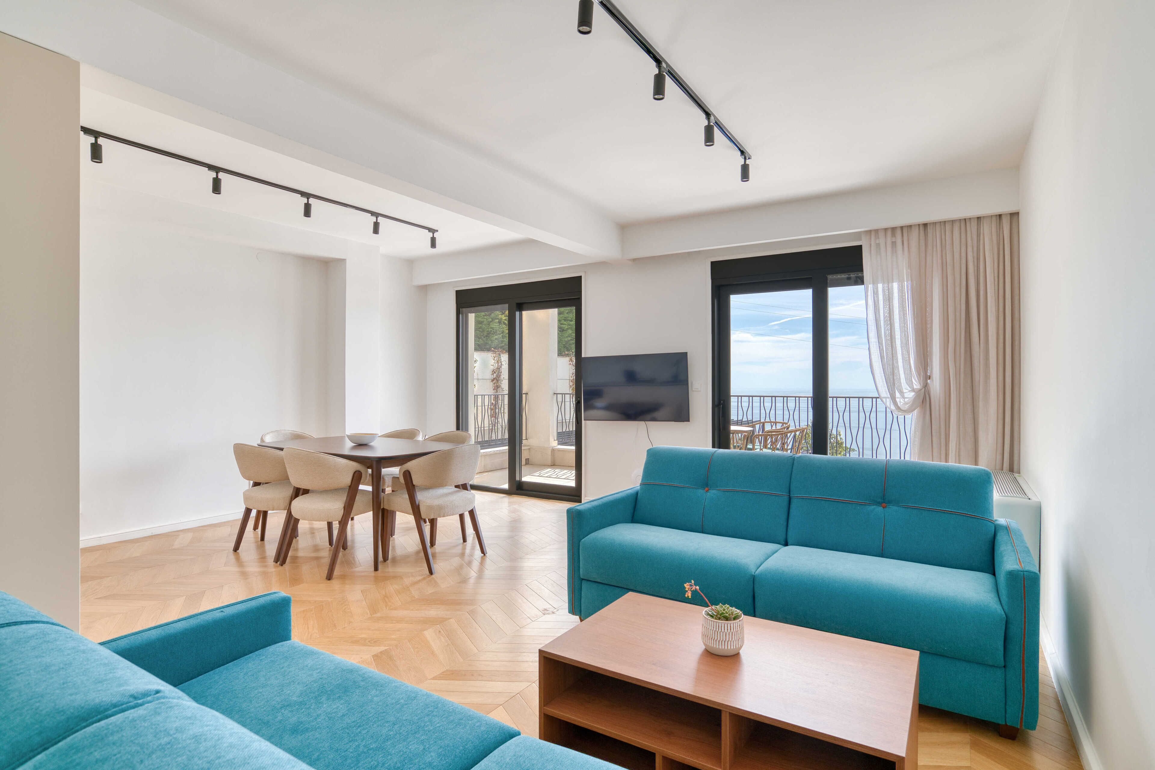 Un saló modern amb un sofà, una taula de centre i una zona de menjador amb cadires i una taula.