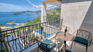 Un balcon agrémenté de meubles en osier, d’une table et d’une bouteille de vin.