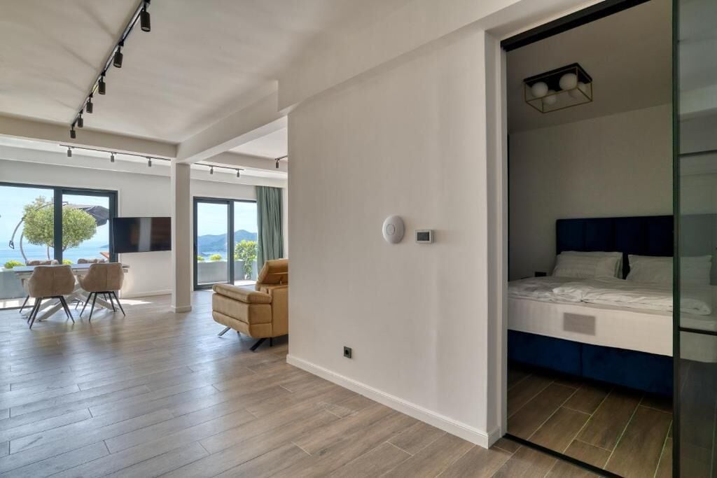 A modern hotel room with a large bed, a seating area with chairs, and a view of the outdoors.
