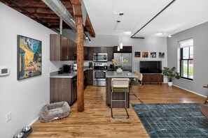 A modern kitchen with wooden cabinets, stainless steel appliances, and a bar area. - Top Floor Loft l Downtown Views l Free Parking l Pet Friendly (Des Moines)