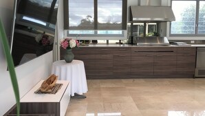 Une cuisine moderne avec un téléviseur à écran plat, un vase de fleurs et un panier à pain posé sur une petite table.