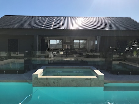 A modern building with a pool, glass railings, and a clear view of the interior.. Paradise Country Living, Nature Retreat near Beaches & Private Chef Fine Dining