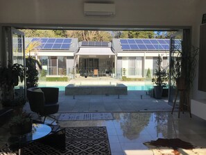 Une maison moderne dotĂ©e dâune piscine, de panneaux solaires et de plantes en pot.