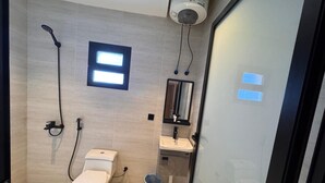 A modern bathroom with a toilet, sink, mirror, shower, and a small window. - RAMA Dubai Serviced Apartments 3 Granada (Riyadh)