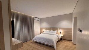 A modern bedroom with a bed, bedside lamps, and a vertical light panel. - RAMA Dubai Serviced Apartments 3 Granada (Riyadh)