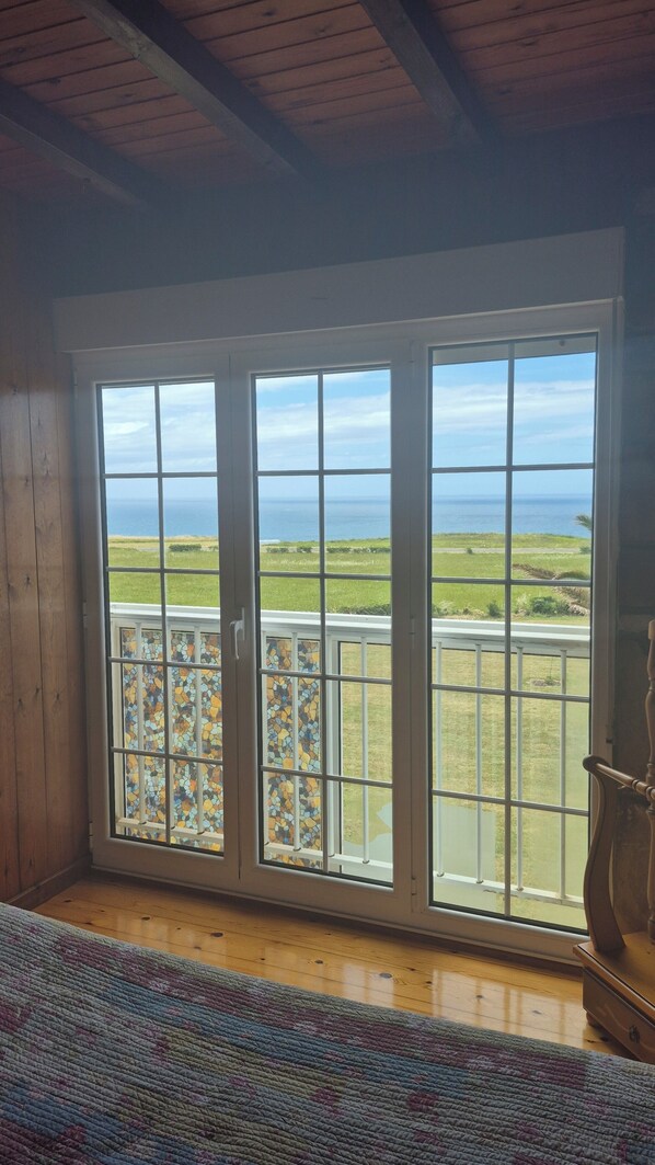 A room with a large sliding glass door leading to a balcony with a view of the ocean.