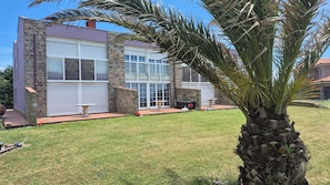 A modern two-story house with stone and stucco exterior, large windows, and a well-maintained lawn.