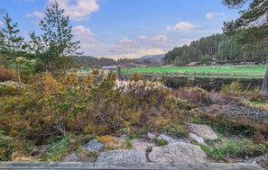 Eine natürliche Landschaft mit einem See, Bäumen und einem Gebäude in der Ferne.