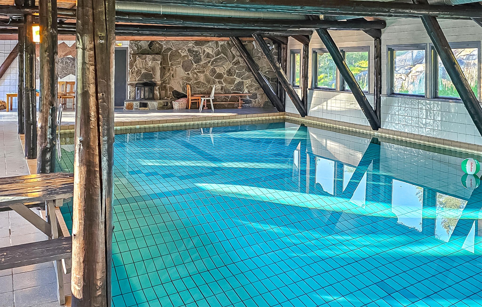 En swimmingpool med klart, blåt vand, omgivet af stenvægge og træbjælker.