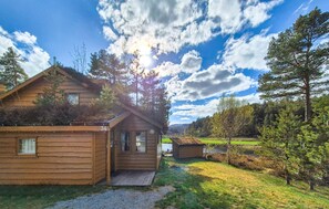 A wooden cabin with a porch, a small shed, and a view of a lake. - Beautiful home in Tjørhom with sauna (Tjørhom)