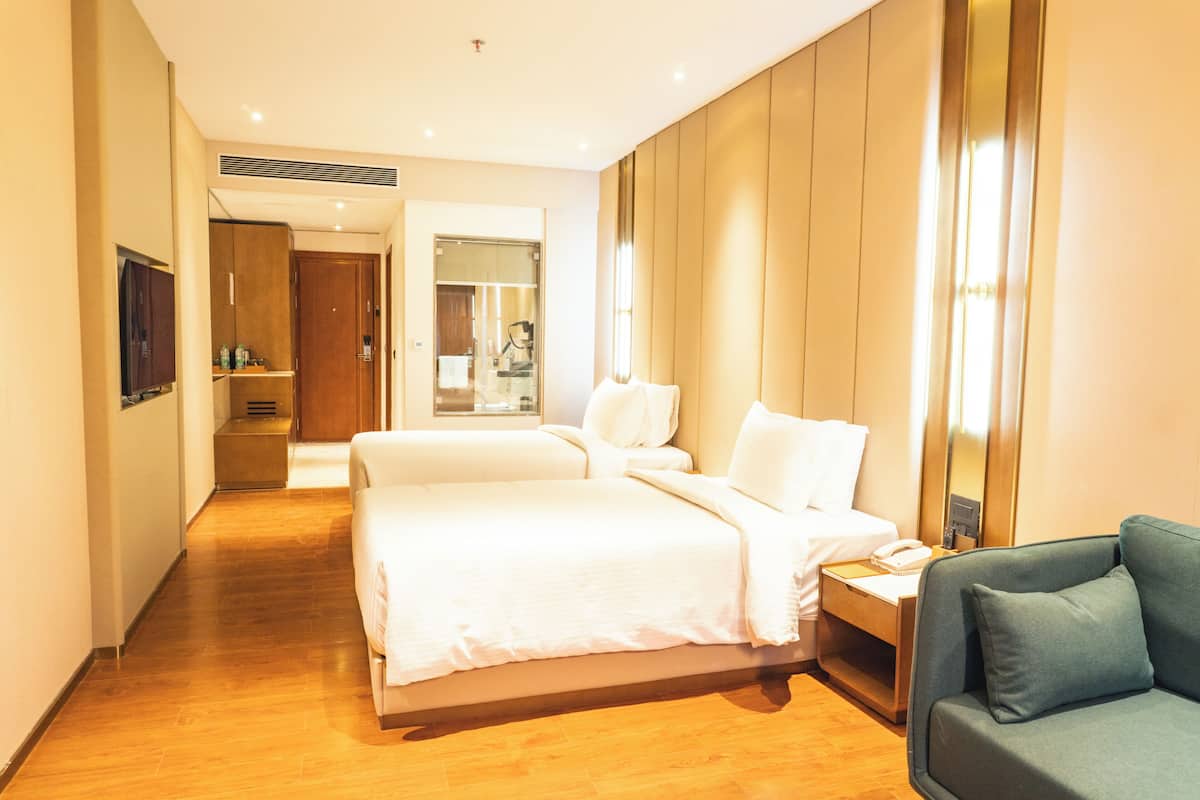 Una habitación de hotel con cama, mesita de noche, una silla, televisión y espejo.