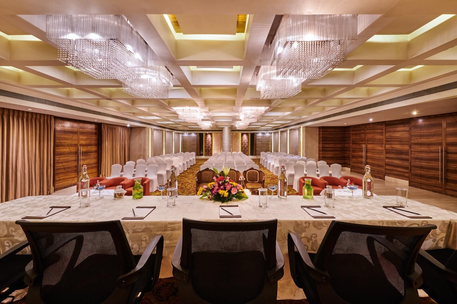 A conference room with a long table, chairs, and chandeliers.