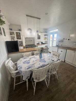 Una cucina moderna con mobili bianchi, un'isola centrale e un'area pranzo con un tavolo rotondo e sedie bianche.