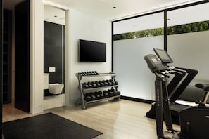 A gym with a treadmill, weight rack, and a flat-screen TV. - Villa Bella (West Hollywood)