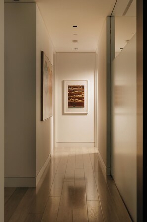 A hallway with a framed artwork on the wall, a wooden floor, and a ceiling light fixture. - Villa Bella (West Hollywood)