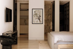 A bedroom with a bed, a desk with a chair, a framed picture on the wall, and a wardrobe. - Villa Bella (West Hollywood)