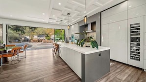 A modern kitchen with a central island, wooden flooring, and a view of the outdoors. - Willow Glen (Los Angeles)