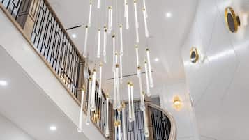A modern staircase with a wooden railing and hanging crystal light fixtures.