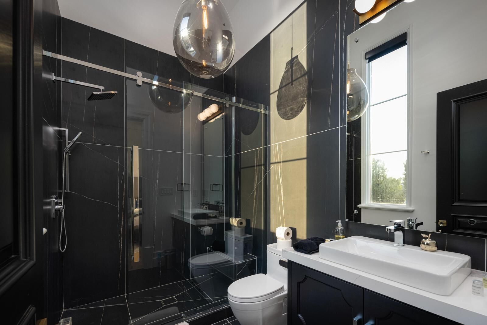 A modern bathroom with a glass-enclosed shower, a white sink, and a large mirror.