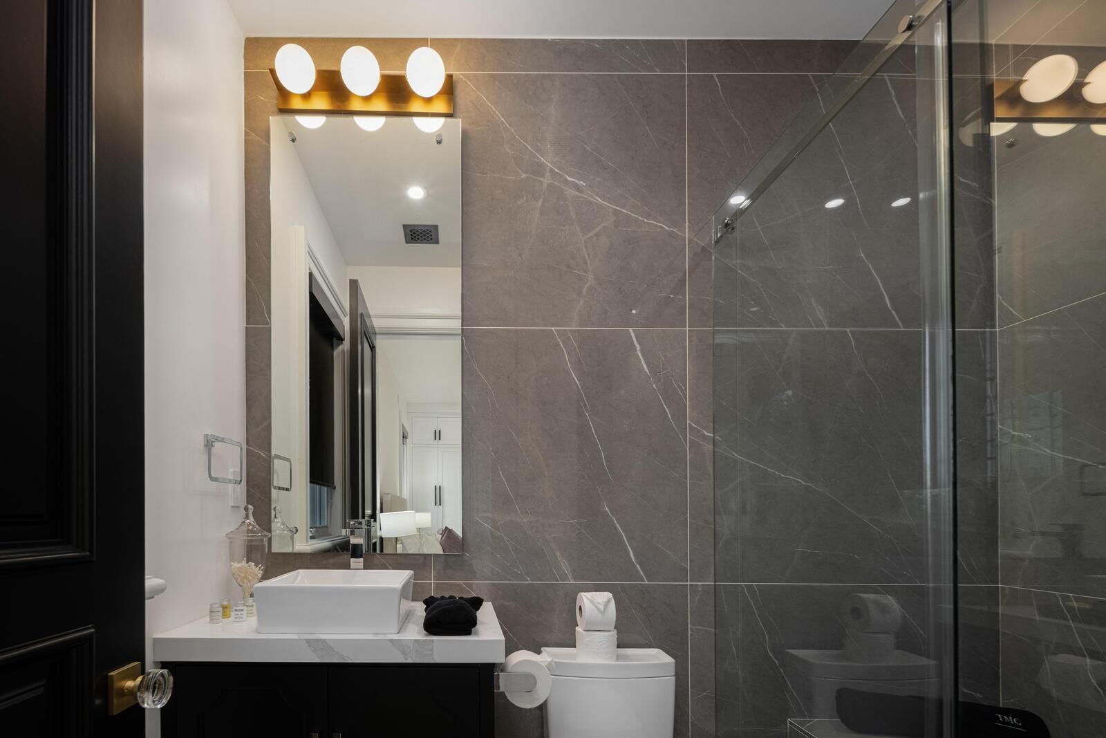 A modern bathroom with a large mirror, a sink, and a shower area.