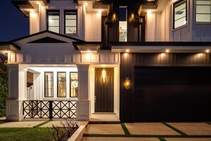Una casa moderna de dos pisos con garaje, ventanas amplias y una entrada bien iluminada.