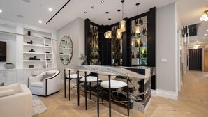 A modern kitchen with a marble island, bar stools, and a wine rack. - Gardner Modern (Los Angeles)