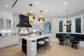 A modern kitchen with marble countertops, a central island, and pendant lighting. - Gardner Modern (Los Angeles)