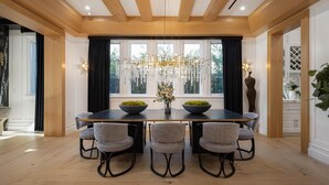 A dining area with a wooden ceiling, a chandelier, and a large window with curtains. - Gardner Modern (Los Angeles)