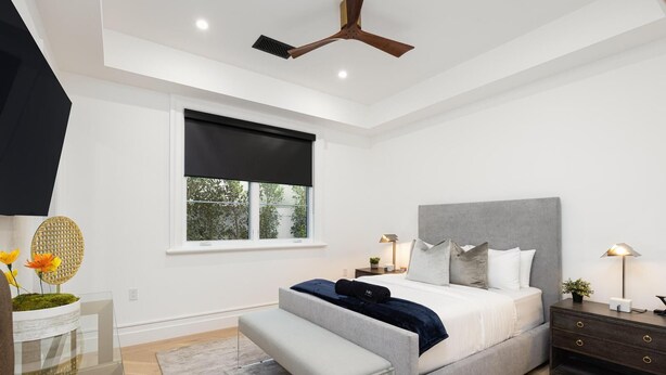 A modern bedroom with a large bed, bedside tables, a bench, and a ceiling fan. - Gardner Modern (Los Angeles)