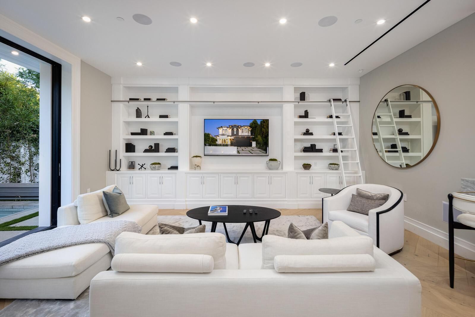 Uma sala de estar moderna com um amplo sofá em formato de L, uma mesa de centro e prateleiras embutidas com livros e objetos decorativos.