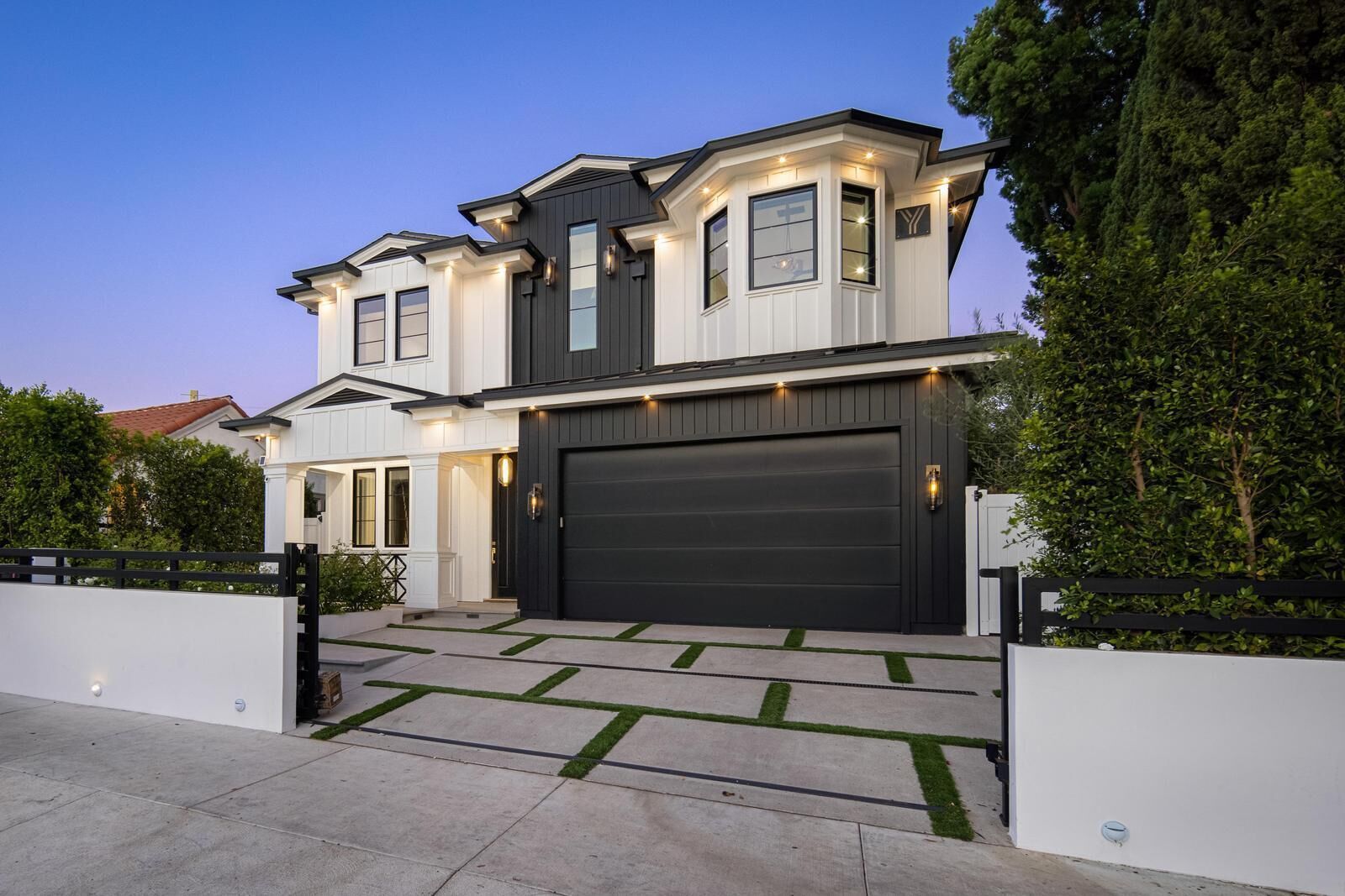 A two-story house with a large garage door, a covered driveway, and a well-maintained lawn.