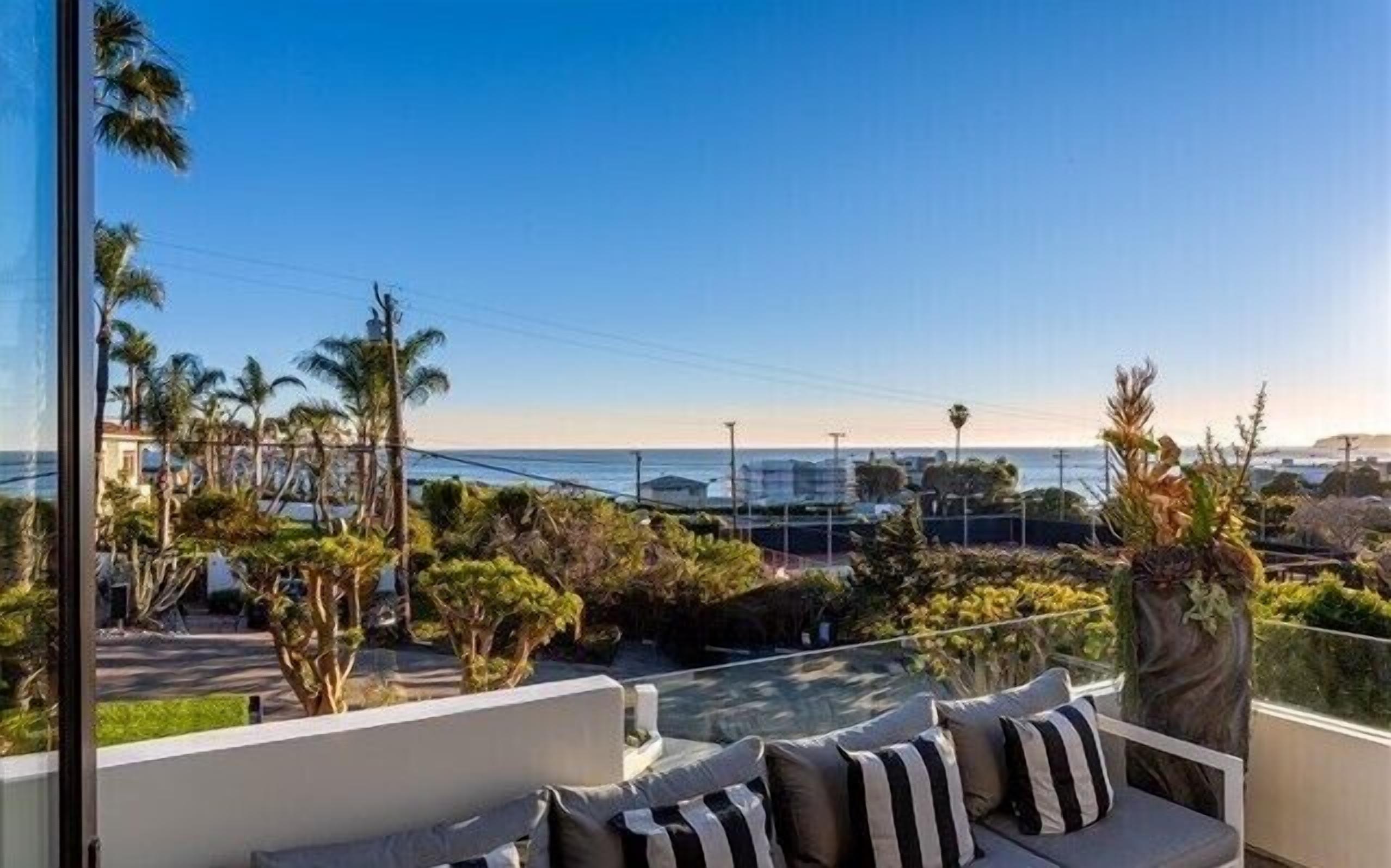 Un balcón con sofá, vista a la ciudad y palmeras.