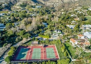 An aerial view of a residential area with a tennis court surrounded by houses and greenery. - Sea Vista (Malibu)