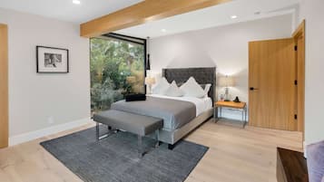 A modern bedroom with a large bed, a bench, a bedside table, and a wardrobe.