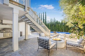 Un patio con mobiliario exterior, una fogata y una piscina.