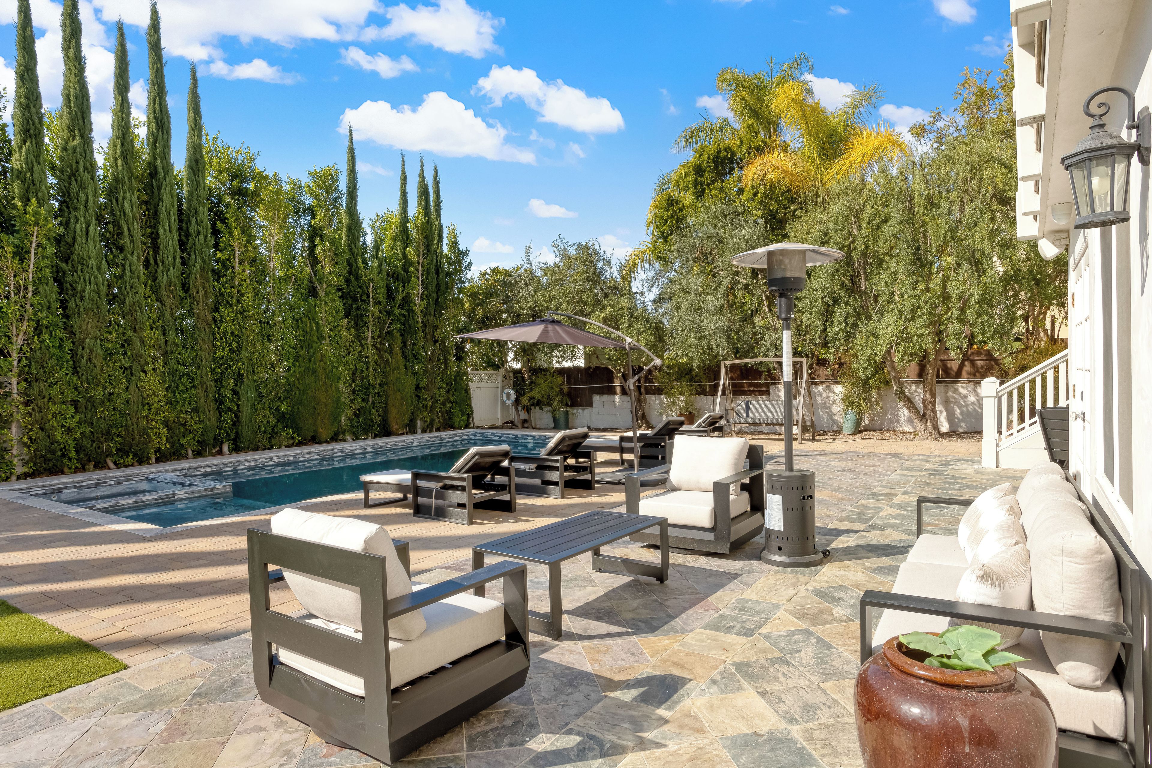 An outdoor pool area with lounge chairs, a table, and a pergola.