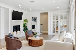 Un salon spacieux doté d’une cheminée, d’un grand téléviseur à écran plat et d’un coin salon confortable.