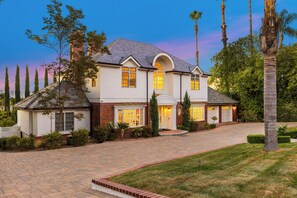 A two-story house with a brick facade, a large front porch, and a driveway leading to a garage. - Emerson Estate (Sherman Oaks)
