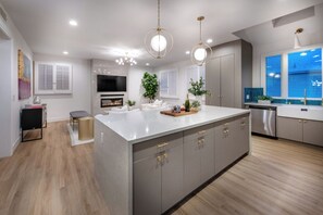 A modern kitchen with a large island, built-in appliances, and pendant lighting. - Reef Mall (Marina del Rey)