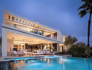 Ein modernes, zweistöckiges Haus mit Swimmingpool, Außenbereich und gut beleuchtetem Innenraum.