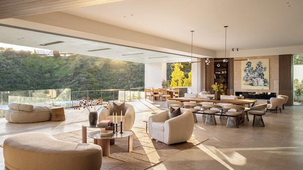 A spacious living area with a large dining table, comfortable seating, and a view of a lush landscape. - Stradella Mansion (Los Angeles)