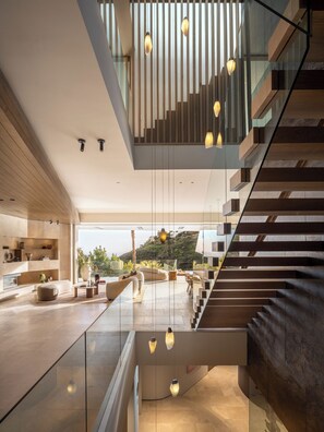 Ein modernes Interieur mit Treppe, Glastrennwand und Pendelleuchten.