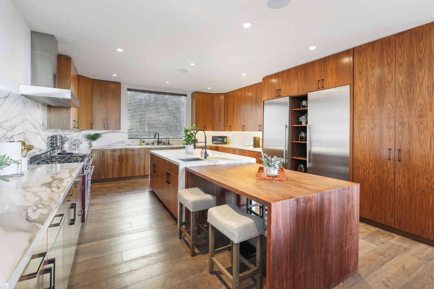 A modern kitchen with wooden cabinets, a marble countertop, and stainless steel appliances.