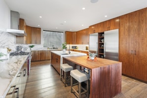 A modern kitchen with wooden cabinets, a marble countertop, and stainless steel appliances. - Franklin Modern (West Hollywood)