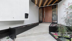 A modern interior with a wooden ceiling, a black bench, and a planter with flowers. - Franklin Modern (West Hollywood)