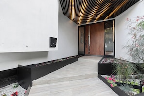 A modern interior with a wooden ceiling, a black bench, and a planter with flowers. - Franklin Modern (West Hollywood)