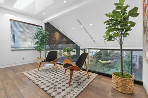 A modern living room with a large window, two chairs, a patterned rug, and a potted plant. - Franklin Modern (West Hollywood)