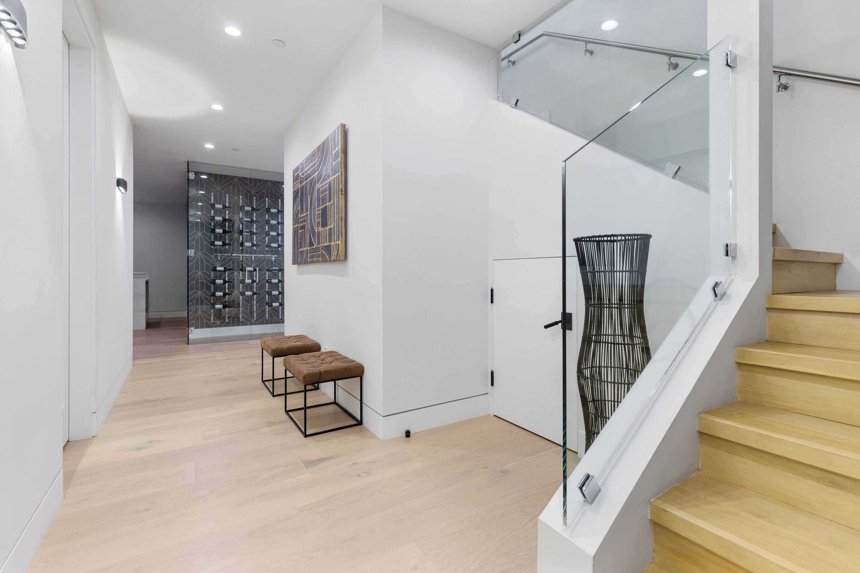 A modern interior with a staircase, wooden flooring, and a glass railing.
